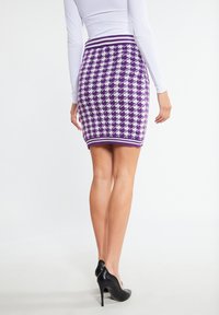Paars en witte houndstooth-gepatenteerde gebreide rok met een aansluitend ontwerp, voorzien van een geribde tailleband en een zoomlijn boven de bovenbenen.