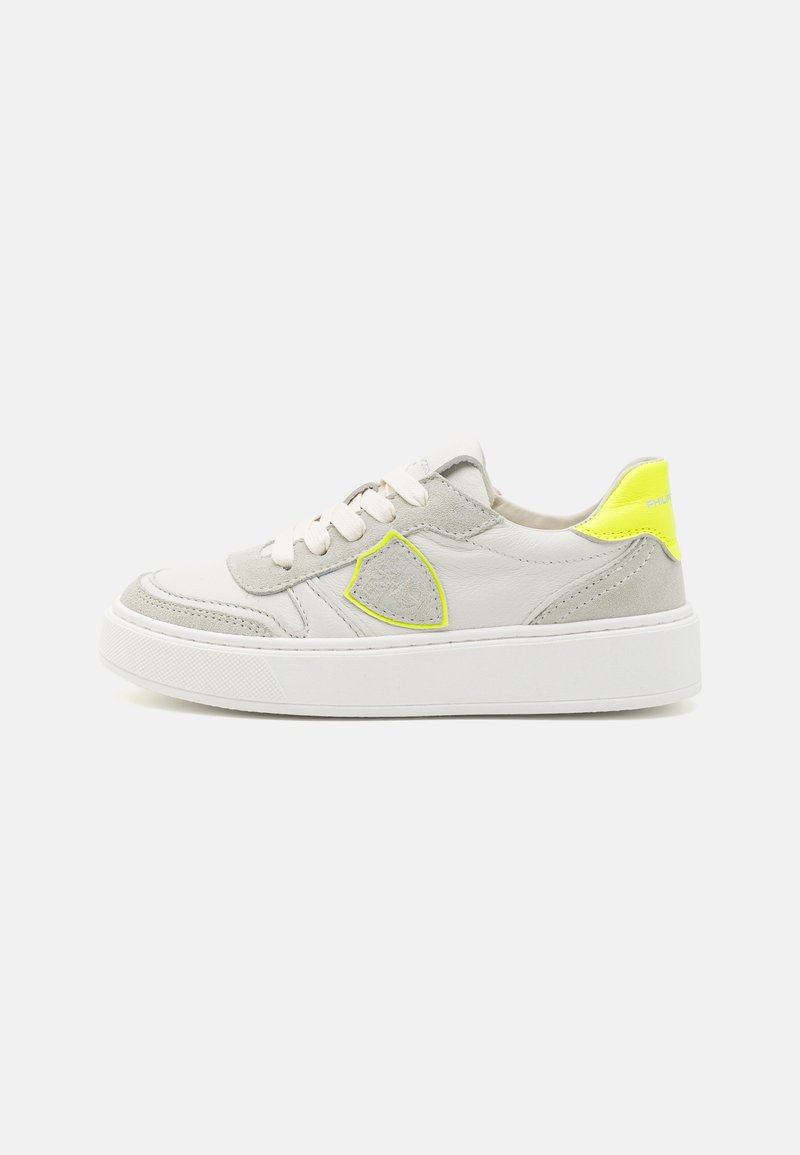 Hellgraue Sneaker aus einer Mischung von Leder und Wildleder. Sie verfügen über eine weiße Sohle, blassrosa Schnürsenkel und einen leuchtend gelben Akzent an der Ferse.