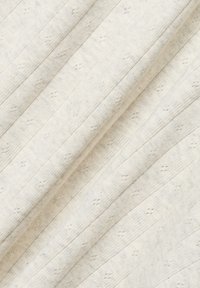 Helles beiges Baumwollgewebe mit subtilen erhabenen Mustern und vertikalen Rippungen, das eine weiche, gewebte Oberfläche zeigt.