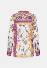 Blouse à manches longues avec motifs floraux multicolores et motifs cachemire en violet, jaune, orange et rouge sur fond blanc, vue de dos.