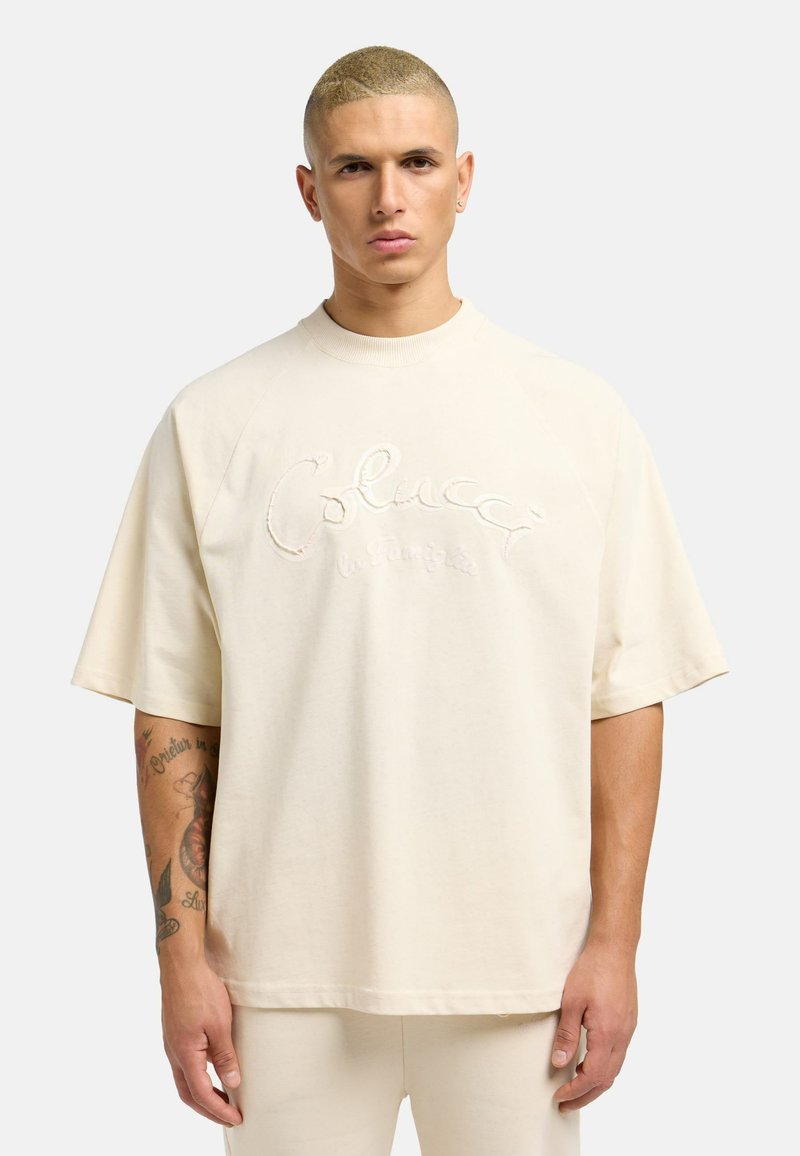 Kremfarget oversized t-skjorte laget av myk bomull. Har hevet broderi med "Colucci" tekst og rugby-stil raglanermer.