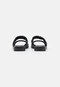 Zwarte platte sandalen met geplooide elastische bandjes en een gladde, ronde neus. Funkioneert met een minimalistisch ontwerp en een laag profiel zool.
