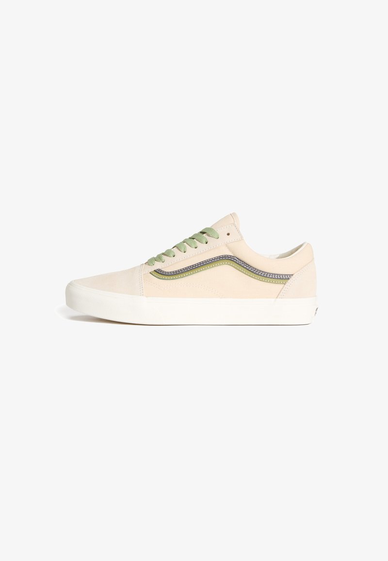 Zapatilla baja beige con raya lateral verde y negra, cordones verdes y suela de goma blanca sobre fondo blanco, vista lateral.