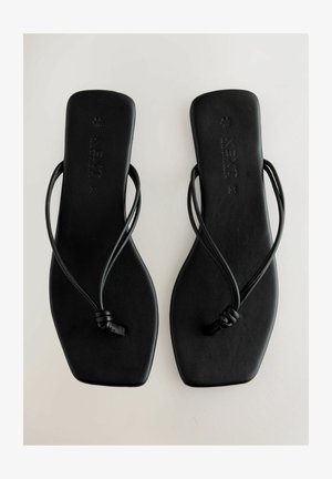 Zwarte platte sandaal met een minimalistisch ontwerp, voorzien van een dunne band en een platte zool. Gemaakt van glad materiaal met een subtiele textuur.