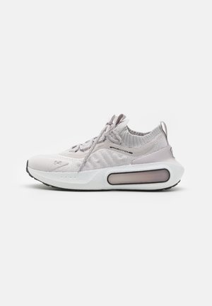 Scarpa sportiva grigio chiaro con tomaia in maglia testurizzata, design con lacci, collo imbottito e una suola prominente e ammortizzata con una tasca d'aria trasparente.