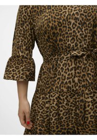 Abito con stampa leopardata realizzato in tessuto morbido; presenta maniche a campana, una cintura in vita e una gonna svasata. La palette dei colori include tonalità di marrone e nero.
