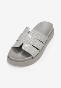 Sandalia de slide gris con un upper texturizado con diseño de cocodrilo, dos correas cruzadas anchas y una suela gruesa. Acabado liso y minimalismo en la marca.
