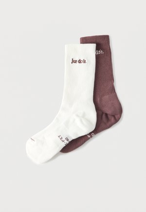 Une paire de chaussettes côtelées, une blanche et une marron, toutes deux avec le texte « Just do it. » brodé près du haut.