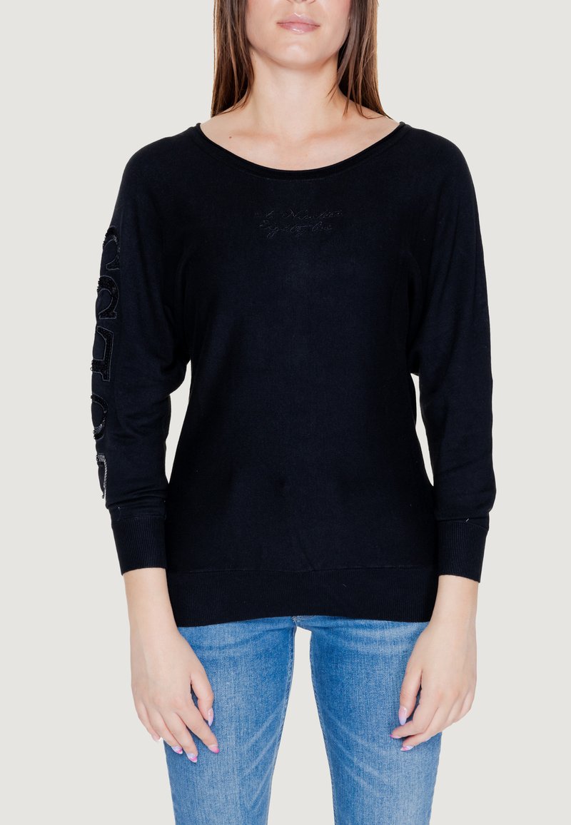 Maglione nero a maglia con vestibilità ampia, scollatura larga e maniche lunghe. Presenta lettere testurizzate lungo la manica sinistra e polsini a costine.