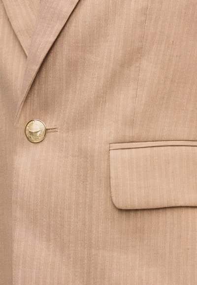 Μπεζ σακάκι με λεπτές κάθετες ρίγες, χρυσό διακοσμητικό κουμπί και τσέπη με καπάκι στη δεξιά μπροστινή πλευρά.