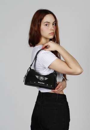 Sac à main en cuir noir avec des accents en argent, présentant un graphisme de Betty Boop et un design d'ailes. Forme compacte et arrondie avec une courte bandoulière.