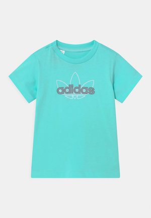 Turkusowa koszulka z krótkim rękawem o okrągłym dekolcie z szarym logo Adidas na przodzie, na środku, nad konturem liścia koniczyny.