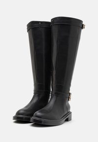 Knee-high czarne botki z gładkiej skóry, z bocznym zamkiem błyskawicznym, złotymi akcentami metalowymi i masywną gumową podeszwą.