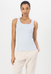 Lichtblauw tanktop met een vierkante halslijn, aansluitend ontwerp, geribbeld textuur en brede schouderbanden, gecombineerd met crème kleurige broeken.