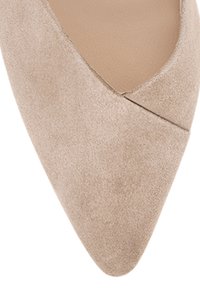 Beige Wildleder-Pumps mit spitzem Zehenbereich, sanfter Textur und dezentem Kreuzdesign an der Vorderseite. Das Innenfutter ist in einem helleren Beige.