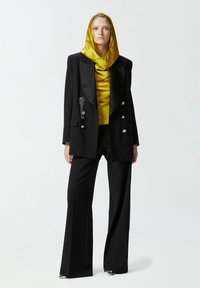 Completo nero con top in satin oro e foulard coordinato. Presenta un design doppiopetto, dettagli gioiello e pantaloni a gamba larga.