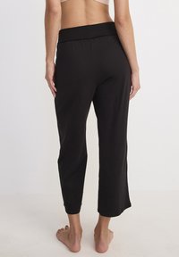 Zwarte capri-broek gemaakt van zachte stof, met een brede elastische tailleband en een comfortabele pasvorm, die tot halverwege de kuit reikt.