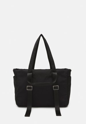 Czarna prostokątna torba typu tote z podwójnymi uchwytami oraz regulowanymi przednimi paskami z srebrnymi klamrami na jednolitym tle.