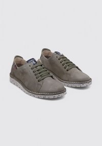 Zapatillas de cuero gris con un diseño de caña baja, cordones verdes y una suela de goma moteada. Presentan una etiqueta de marca en la lengüeta.