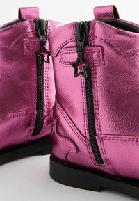 Rosa metallische Knöchelstiefel mit schwarzem Reißverschluss und sternförmigem Ziehschneider, dekorativer Naht und einer soliden schwarzen Sohle.