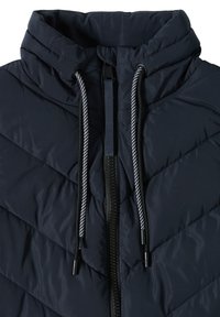 Veste matelassée bleu marine avec col montant, fermeture éclair noire et deux cordons rayés noir et blanc à l'encolure.
