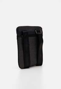 Black shoulder bag features textured fabric with a subtle logo pattern, zip closure, and sturdy adjustable straps for ease of carry.