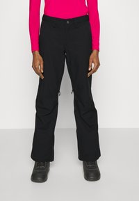 Black ski pants with a straight cut, featuring zippered vents and a sturdy waistband. Paired with insulated black winter boots.