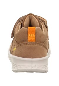 Braune Leder-Sneaker mit einem Klettverschluss, ausgestattet mit einem strukturierten Obermaterial, weißer Gummisohle und einer orangefarbenen Fersenschlaufe.