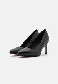 Chaussures à talons hauts en cuir noir avec un bout pointu, un design élégant et une hauteur de talon modérée, présentant une texture lisse sans motifs.