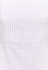 Lähikuva vaaleanliilasta ja valkoisesta ruudullisesta kankaasta, jossa on istuvuusviimeistely.