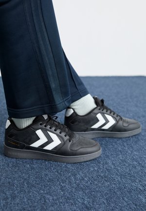 Sneakers neri con accenti a chevron bianchi, dotati di una tomaia in pelle liscia, punta rotonda, design con lacci e suola in gomma sottile.