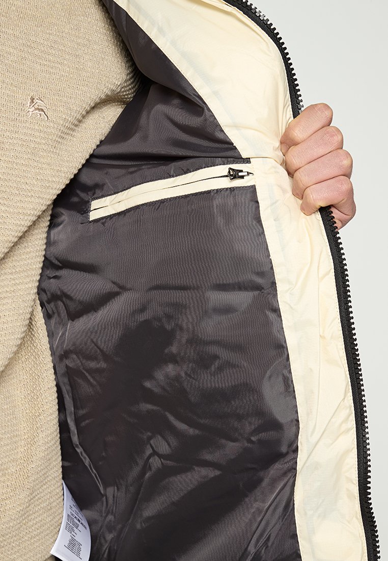 Leichte Jacke mit einem Innenfutter in hellcreme und einem äußeren Material in dunkelgrau, ausgestattet mit einer Reißverschlusstasche innen und einer glatten Textur.