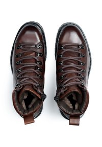 Bottes de randonnée en cuir marron avec une finition lisse, des œillets en métal, des lacets gris et des semelles intérieures en fourrure. Comprend une languette à l'arrière pour un enfilage facile.