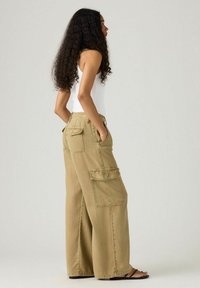 Bredde cargo bukser i lys khaki stof, med to sidelommer, baglommer og en løs pasform. Stylet med en hvid tanktop.