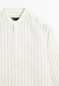 Chemise blanche à boutons avec fines rayures verticales grises et col officier, présentée à plat montrant le devant et la manche droite.