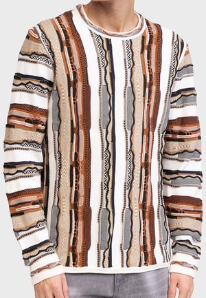 Man wearing a long-sleeve sweater with vertical multicolored textured stripes in brown, beige, black, and white tones.
