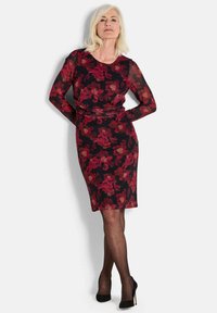 Schwarzes und rotes Blumenkleid mit langen transparenten Ärmeln, figurbetontem Design, knielangem Saum und glatter Textur. Schwarze High Heels.