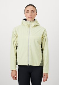 Chaqueta con capucha de color amarillo claro, con cremallera en el frente, acentos negros a los lados, paneles texturizados y diseño ajustado. Adecuada para actividades al aire libre.