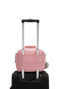 Valigia nera con manico estensibile sopra cui poggia una piccola borsa di tessuto rosa con zip e un accentuazione di pompon grigio.