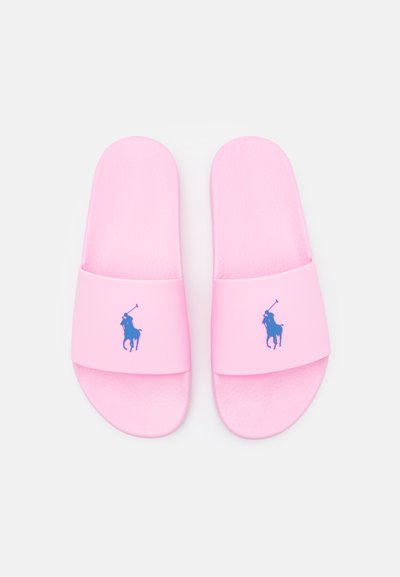 Chinelas de borracha rosa com uma sola texturizada e tiras largas. Apresentam um logotipo azul de um cavalo e cavaleiro na tira.