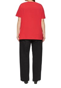 Rode katoenen t-shirt met een relaxed fit, korte mouwen en een ronde halslijn, gecombineerd met zwarte wijd uitgeslagen broek met rafelige zomen.