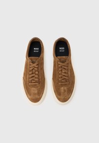 Καφέ σουέντ αθλητικά παπούτσια με στρογγυλεμένη μύτη, σχέδιο με κορδόνια, μπεζ λαστιχένια σόλα και λεπτή ραφή στον ίδιο τόνο. Λογότυπο στην εσωτερική σόλα.