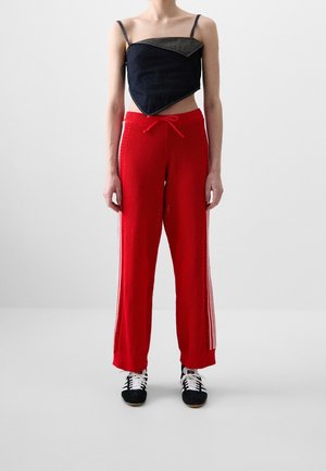 Svart och denimmönstrad kort topp, röda stickade vida byxor med sidostripes, bärs med svart och vita skor. Enkelt design och avslappnad passform.