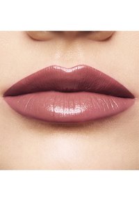 Lippenprodukt mit einem glatten, glänzenden Finish in einem gedämpften Mauve-Ton. Die Form ist prall und gut definiert und zeigt subtile Textur und Dimension.