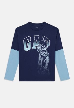 Marineblaues Langarm-T-Shirt mit dem Schriftzug "GAD" in fetten Buchstaben, hellblauen Ärmeln und einer Grafik eines Footballspielers im Profil. Aus weichem Baumwollmaterial.