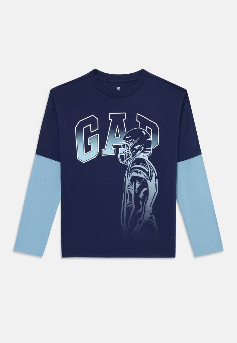 Tricou cu mânecă lungă de culoare bleumarin, având inscripția "GAD" cu litere îndrăznețe, mâneci de culoare albastru deschis și o grafică cu un jucător de fotbal în profil. Material din bumbac moale.