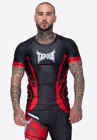 Rash guard ajustado negro y rojo con el logo de TAPOUT, que presenta un diseño de mangas cortas, patrón de salpicaduras y rayas en contraste.