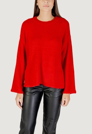 Pull rouge surdimensionné en tissu doux et moelleux, avec un col rond et des manches larges, associé à un pantalon en cuir noir.