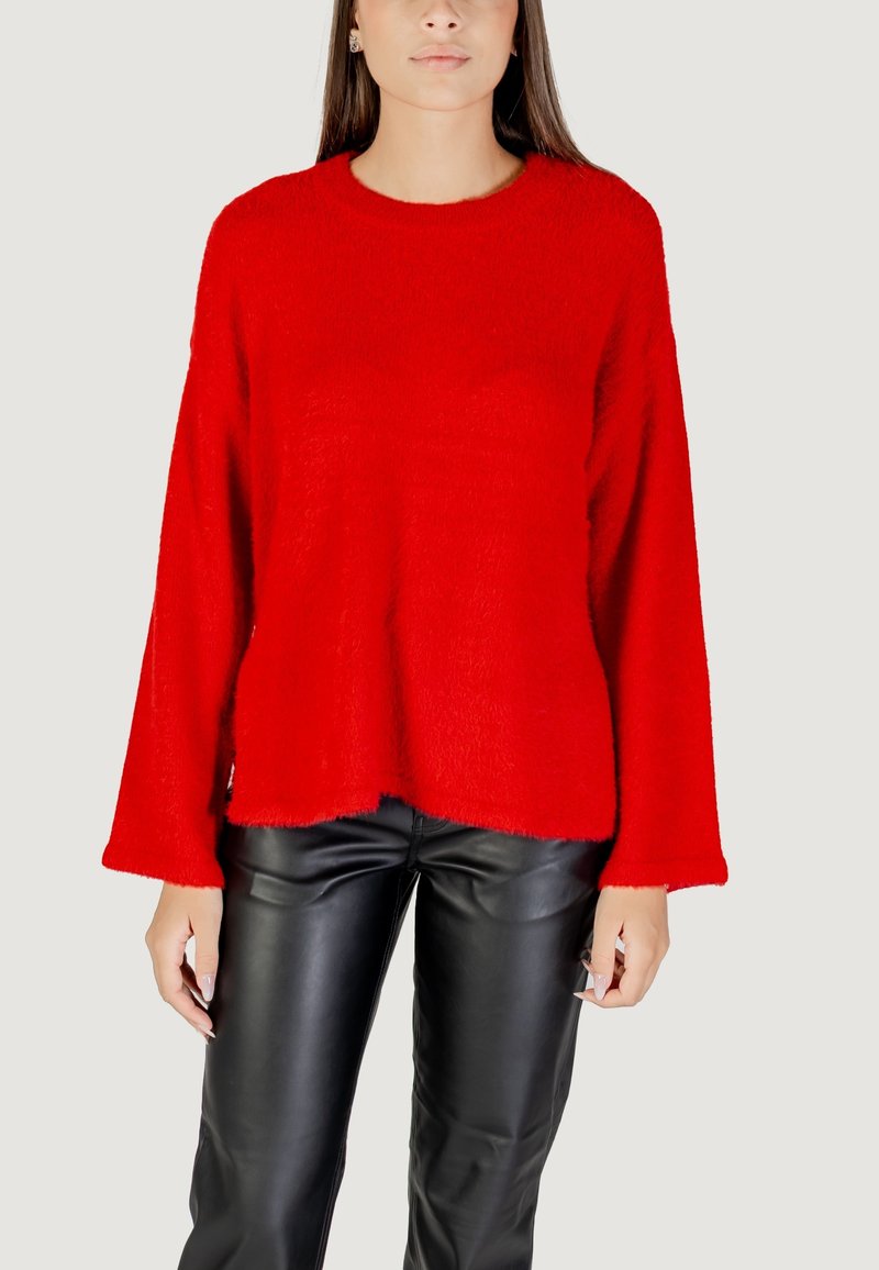 Maglione rosso oversize realizzato in un morbido tessuto peloso, con scollo rotondo e maniche ampie, abbinato a pantaloni in pelle nera.