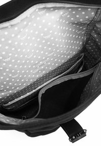 Black bag interior featuring a gray polka dot lining, multiple compartments, and a zippered mesh pocket for organization.